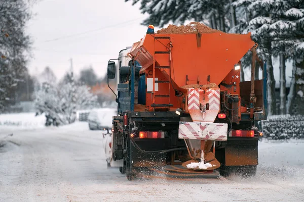 Snowplow outdoors clean pavement sidewalk road driveway. Winter weather. Snow Plow orange  Truck Clears the Road of Ice and Snow in Winter. Snow removal and adding Sand with Salt mixture to the Road.