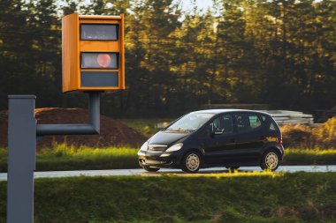Radar donanımlı bir hız kamerası yoldaki trafiği izler, hız limitini aşan bir arabayı yakaladığında sarı ışık yakar ve aracı tanımlamak ve yasaları uygulamak için teknolojiyi kullanır..