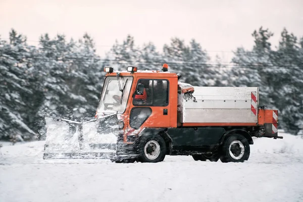Tractor with mounted salt and sand spreader, road maintenance - winter gritter vehicle. Municipal service melting ice and snow on streets. Diffusing salt blend on  public roads.