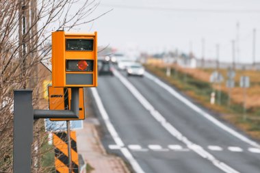 Sarı hız kamerası, bir otoyolda hız yapan bir arabayı algılarken, radar ve yapay zeka kullanarak plakayı fark eder ve ceza olarak....