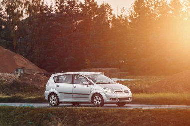 Kırsalda araba hız yapıyor. Modern bir hatchback 'in içinde yeşilliklerle çevrili bir yolda hızlı sürüyorum. Otoyolda ilerleyen modern hatchback 'in yan görüntüsü.