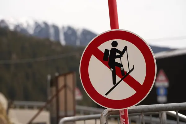 A no ski climbing sign prominently displayed against a backdrop of distant mountains and a metal barrier. Amidst nature\'s beauty lies danger heed the warning signs to ensure a safe experience.