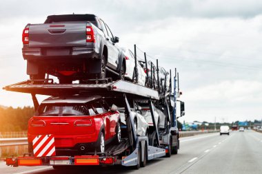 Araba pazarı için yeni jipleri olan hidrolik bir karavan. Karavan, yolda hızlı giden bir nakliye aracına bağlı. Römork, iki katlı modüler rampasında birçok araba taşıyabilir..