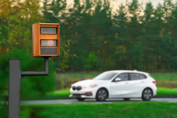 A yellow speed camera flashes as it detects a speeding car on a highway, using radar and artificial intelligence to recognize the number plate and issue a fine.