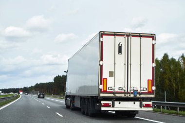 Mal teslimatı ve nakliyesi yarı karavan kamyonlarıyla. Kamyonlar kargo konteynırlarıyla yolda ilerliyorlar. Sürdürülebilir ve verimli ulaşım sistemi kavramı. Arazi lojistik endüstrisi modeli.