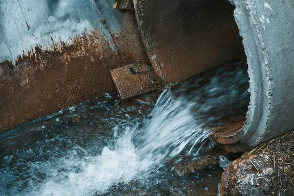 A drainpipe discharges sewage into the water, causing environmental damage and ecological imbalance.