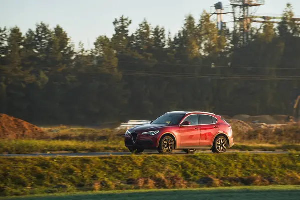 Otobandaki kırmızı araba. Yaz günbatımında hız ve seyahat için spor ve lüks bir SUV aracı..