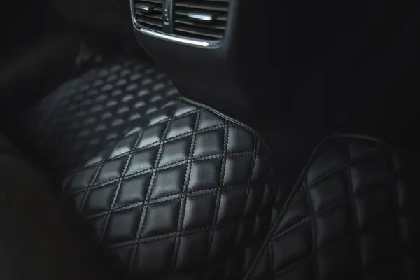 Premium luxury leather floor mat in a modern car interior. Auto service industry. Second row interior of a premium car with floor car mat. The modern, sophisticated and luxurious interior design.