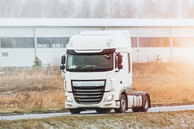 Modern white truck with diesel engine on the highway without a trailer. Semi truck isolated close-up.