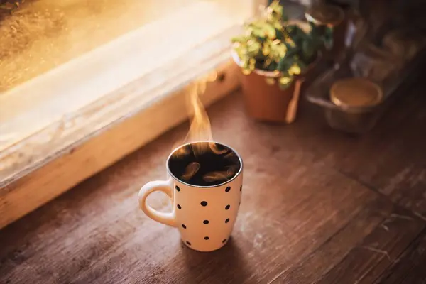 A steaming cup of coffee bathed in the soft glow of morning light brings warmth and comfort to start the day. Golden sunlight illuminates a polka-dotted mug filled with hot beverage.