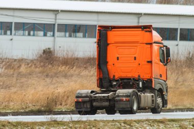 Açık bir yolda römorksuz giden bir kamyon. Avrupa modern kamyoneti dizel motorla çalışır. Yol yabani otlar ve uzak bir sanayi bölgesiyle çevrili..