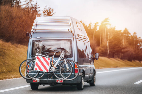 A bike and a camper van on the highway. A family adventure in Europe with a mobile and recreational vehicle that has a bicycle on the rear.
