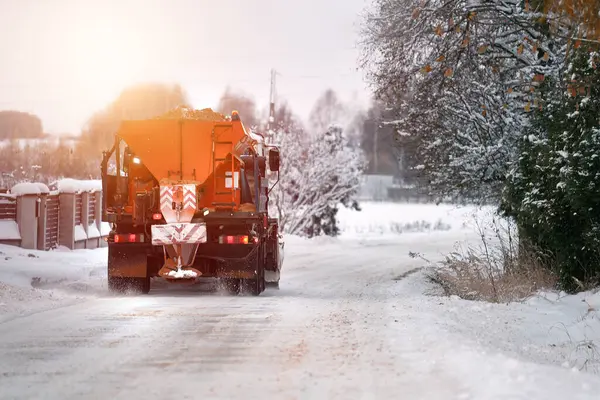 A snowplow truck applies salt and sand as the truck works to clean the snowy road. How salt and sand damage the metal parts of a truck plowing the snow on a winter road