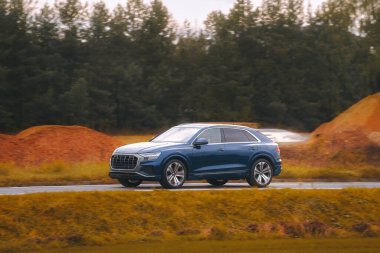 Modern bir aile arazi aracı görkemli bir doğa ve arka planda altın bir günbatımına sahip manzaralı bir yol boyunca seyahat eder. Daha fazla off-road kapasitesine ve 4WD AWD 4x4 moduna sahip subcompact kamyon.