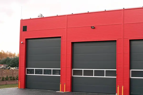Modern independent workshop garage doors. Gray Garage Doors are set against a Striking Red Wall. Industrial garage in black and red colors.