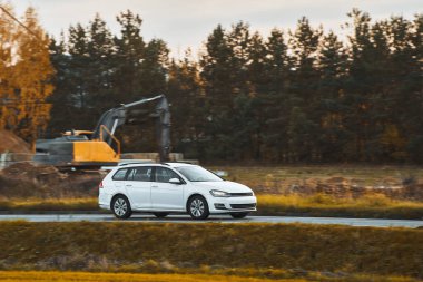 Doğayla çevrili bir otoyolda hız yapan melez bir araç. Bir aile, günbatımının büyüleyici ışığında sürdürülebilir ve modern bir yolculuğun tadını çıkarır..