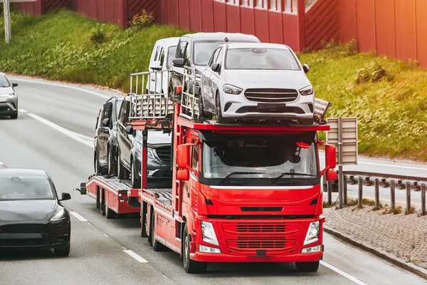 stock image Car dealership delivery. New cars on a hydraulic trailer are ready for delivery and sale. A car transporter truck carries many cars on a two-level modular ramp.