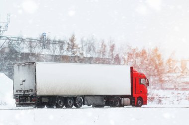 Kış yolunda yarı kamyon. Kar fırtınasından sonra soğuk havada mal taşıyan büyük bir sanayi kamyonu..