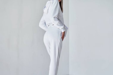 Bu çağdaş Beyaz Toplulukla Üstünkörü Gelişigüzel Deneyin. Spor giysi modeli. Beyaz pantolonlu kız. Beyaz, minimalist eşofman giyen genç bir kadının arka plan görüntüsü..