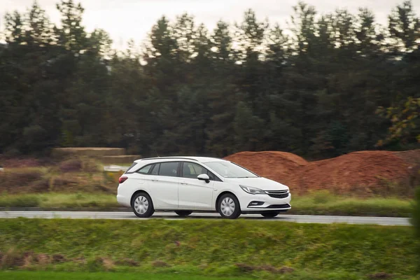 Büyüleyici alacakaranlık ışığı altında sakin bir orman manzarasının arka planında çekilmiş bir araba yolculuğu. Modern aile aracı otoyolda ilerliyor. Sürdürülebilir yolculuk.