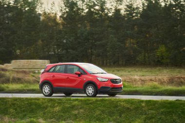 Modern bir aile arazi aracı görkemli bir doğa ve arka planda altın bir günbatımına sahip manzaralı bir yol boyunca seyahat eder. Daha fazla off-road kapasitesine ve 4WD AWD 4x4 moduna sahip subcompact kamyon.