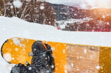 Karla kaplı dağların ve yamacın snowboardcu perspektifi. Gökyüzü bulutlu ve beyaz, sakin bir his veriyor..