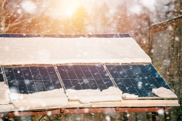 Solar panels are covered with snow in winter. Photovoltaic electricity installation during the winter season. Alternative energy home production in cold weather.