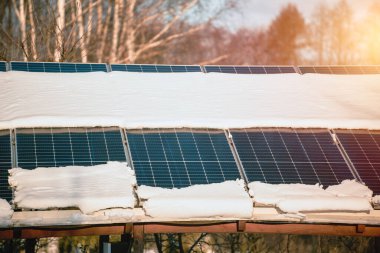 Güneş panelleri kışın karla kaplıdır. Kışın fotovoltaik elektrik tesisatı. Soğuk havada alternatif enerji üretimi.