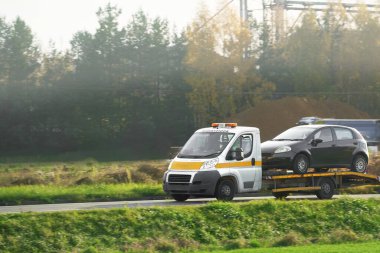 Otobanda bozuk bir araba. Çekici servisi, çarpışmadan sonra hasarlı aracı olan bir adama yardım ediyor. Çekici yolda bozuk bir araba taşıyor..