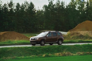 Modern bir aile arazi aracı görkemli bir doğa ve arka planda altın bir günbatımına sahip manzaralı bir yol boyunca seyahat eder. Daha fazla off-road kapasitesine ve 4WD AWD 4x4 moduna sahip subcompact kamyon.
