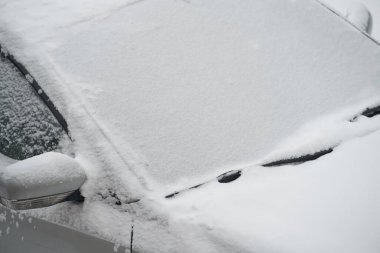 Kış günü, buz ve karla kaplı donmuş bir arabanın ön camı. Şehirde karla kaplı araba ön camı. Arabanın ön camını kapat..
