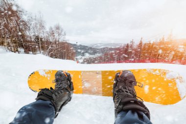 Karla kaplı dağların ve yamacın snowboardcu perspektifi. Gökyüzü bulutlu ve beyaz, sakin bir his veriyor..