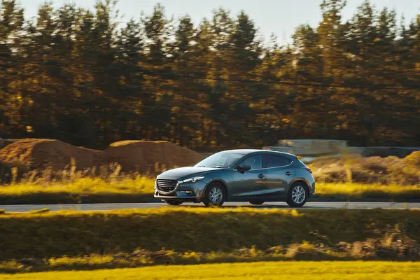 Kırsalda araba hız yapıyor. Modern bir hatchback 'in içinde yeşilliklerle çevrili bir yolda hızlı sürüyorum. Otoyolda ilerleyen modern hatchback 'in yan görüntüsü.