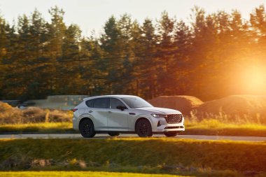 Modern bir aile arazi aracı görkemli bir doğa ve arka planda altın bir günbatımına sahip manzaralı bir yol boyunca seyahat eder. Daha fazla off-road kapasitesine ve 4WD AWD 4x4 moduna sahip subcompact kamyon.