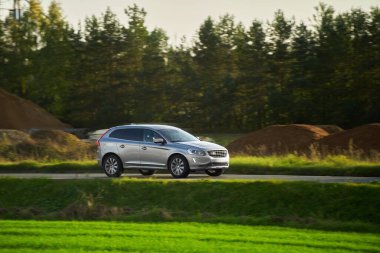 Modern bir aile arazi aracı görkemli bir doğa ve arka planda altın bir günbatımına sahip manzaralı bir yol boyunca seyahat eder. Daha fazla off-road kapasitesine ve 4WD AWD 4x4 moduna sahip subcompact kamyon.