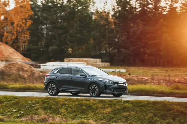 Modern bir aile arazi aracı görkemli bir doğa ve arka planda altın bir günbatımına sahip manzaralı bir yol boyunca seyahat eder. Daha fazla off-road kapasitesine ve 4WD AWD 4x4 moduna sahip subcompact kamyon.