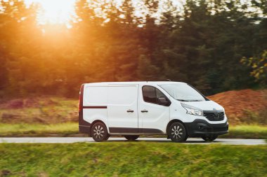 Kendi dağıtım servisini bu beyaz minibüsün maketi ile tasarla. İş logonuz ve isminizle kişiselleştirmeniz için boş bir paket. Farklı manzaralı bir ticari araç yolda izole edilmiş..