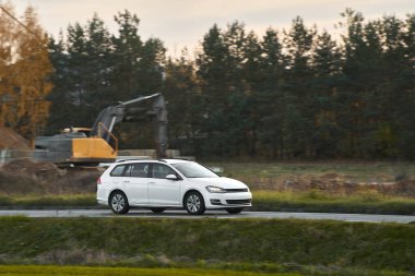 Doğayla çevrili bir otoyolda hız yapan melez bir araç. Bir aile, günbatımının büyüleyici ışığında sürdürülebilir ve modern bir yolculuğun tadını çıkarır..