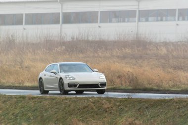 Bir Alman lüks arabası, gün batımının altın rengi ile sakin ormanı aydınlatan manzaralı bir güzergah boyunca sürüyor..