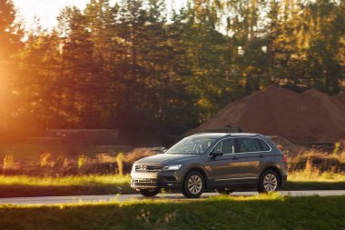 Modern bir aile arazi aracı görkemli bir doğa ve arka planda altın bir günbatımına sahip manzaralı bir yol boyunca seyahat eder. Daha fazla off-road kapasitesine ve 4WD AWD 4x4 moduna sahip subcompact kamyon.