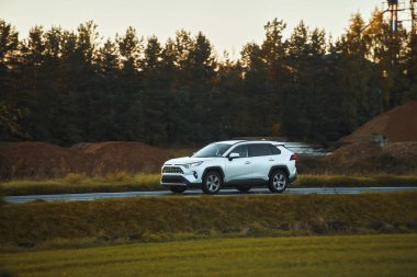 Modern bir aile arazi aracı görkemli bir doğa ve arka planda altın bir günbatımına sahip manzaralı bir yol boyunca seyahat eder. Daha fazla off-road kapasitesine ve 4WD AWD 4x4 moduna sahip subcompact kamyon.