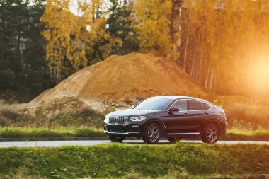 Modern bir Alman lüks otomobilinin zerafeti ve performansı, kırsal kesimde muhteşem bir yolda giderken yan manzarada sergileniyor..