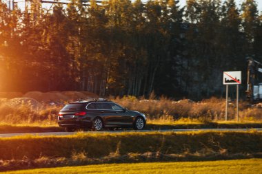 Doğayla çevrili bir otoyolda hız yapan melez bir araç. Bir aile, günbatımının büyüleyici ışığında sürdürülebilir ve modern bir yolculuğun tadını çıkarır..