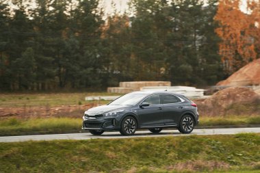 Modern ve lüks bir SUV, altın bir gün batımı gökyüzünün nefes kesici manzarasıyla asfalt bir yolda seyahat eder..