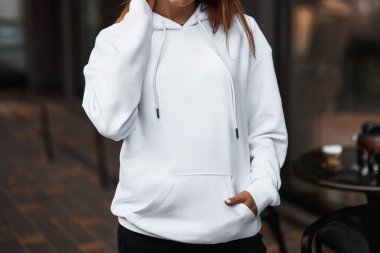 Kapüşonlu bir kadının ön görüntüsü. Beyaz tarafsız arkaplanda yatay stüdyo fotoğrafı. Boş tişörtlü kız..