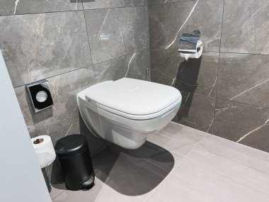 Modern tuvalet banyoda. Banyo kapalı tuvalete bakıyor. Modern bir banyoda yeni seramik beyaz klozet. Dairede rahat ve şık bir tuvalet var..