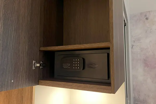An open digital safe on a shelf in the closet with money and documents inside. The safe has a keypad for protection and security. The safe requires a password and a code to lock and unlock it.