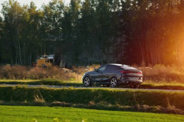 Şık ve hızlı bir Alman lüks arabası gün batımında manzaralı güzel bir yolda sürdürülebilir bir seyahat deneyimi yaşamaktadır..