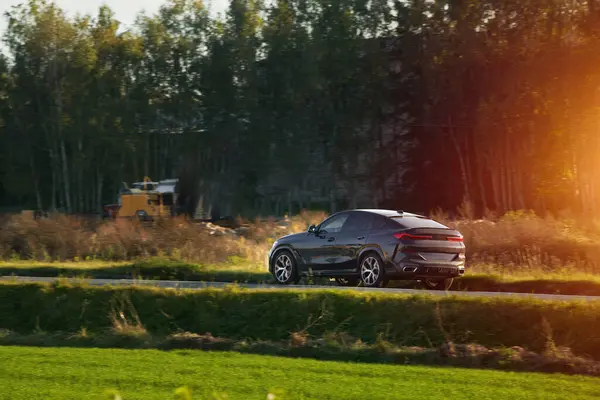 Şık ve hızlı bir Alman lüks arabası gün batımında manzaralı güzel bir yolda sürdürülebilir bir seyahat deneyimi yaşamaktadır..