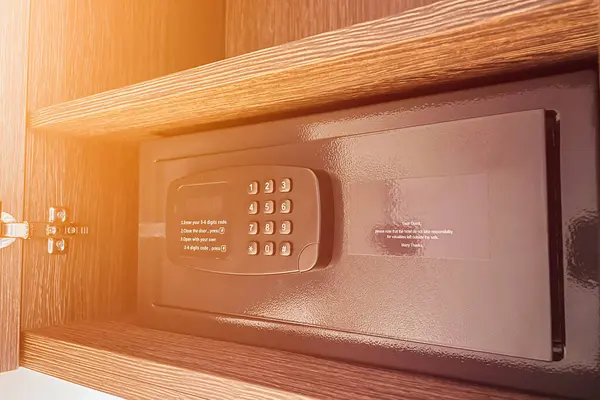 Money and documents in an open digital safe on a closet shelf. The safe has a keypad and a screen for security and protection. The safe can be locked and unlocked with a code and a password.